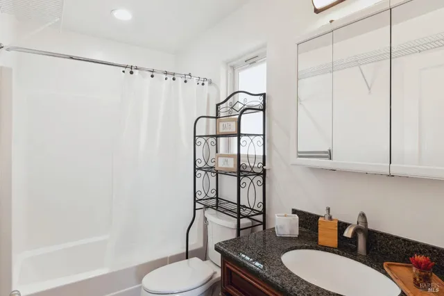 a bathroom with a granite countertop sink toilet and shower