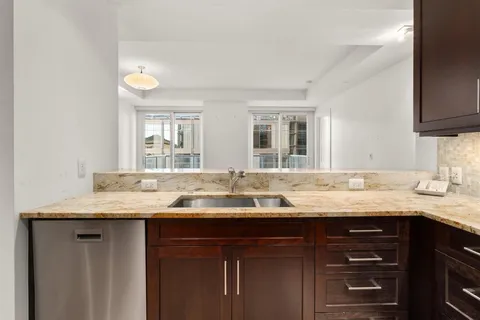 a view of an empty room with kitchen and a window