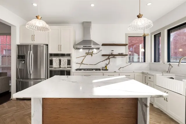a kitchen with stainless steel appliances kitchen island granite countertop a sink a stove and refrigerator