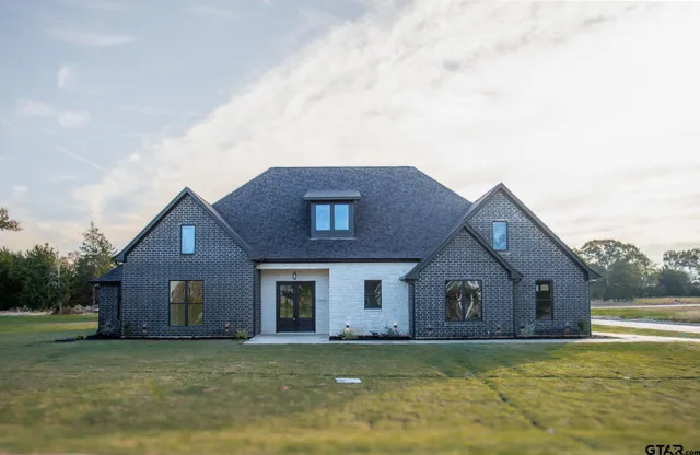 a house that is sitting in a yard with large trees