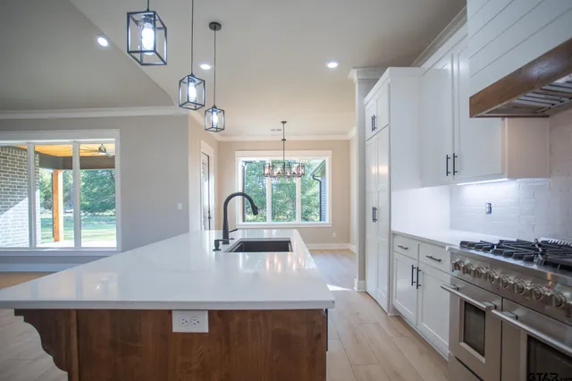 a kitchen with kitchen island granite countertop a stove a sink a center island and windows