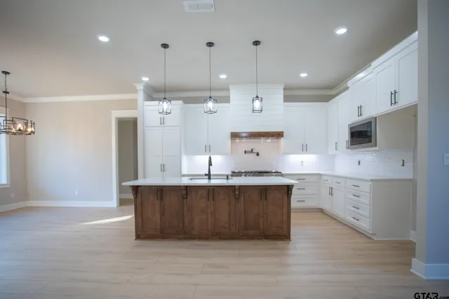 a large kitchen with stainless steel appliances a large counter top a stove a sink and a refrigerator