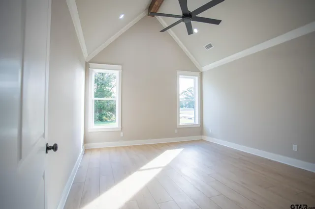 an empty room with wooden floor fan and windows