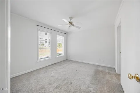 an empty room with windows and ceiling fan
