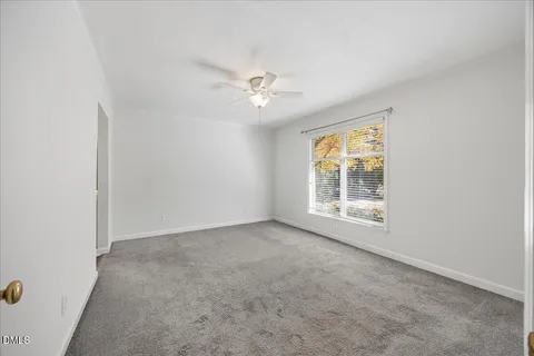 an empty room with a window and a ceiling fan