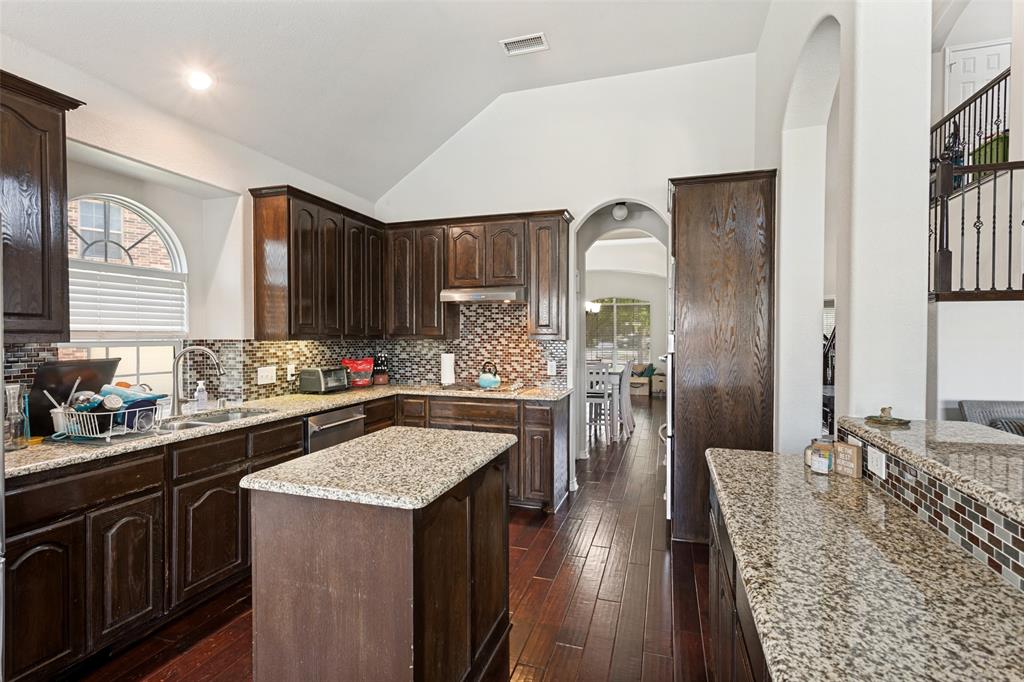 4117 Autumn Path Road Denton, TX 76208 - Photo 6 of 14 Kitchen featuring rich wood cabinetry, granite countertops, an island, and a mosaic tile backsplash