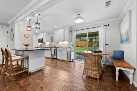a kitchen with stainless steel appliances granite countertop wooden floor a dining table and chairs
