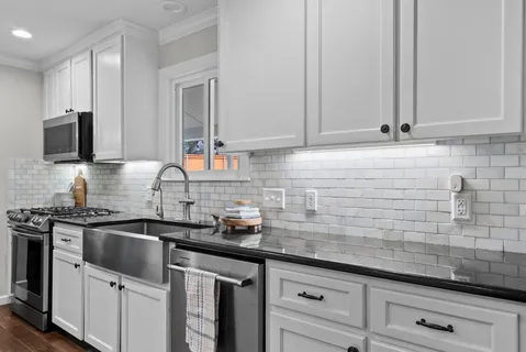 a kitchen with granite countertop white cabinets and stainless steel appliances