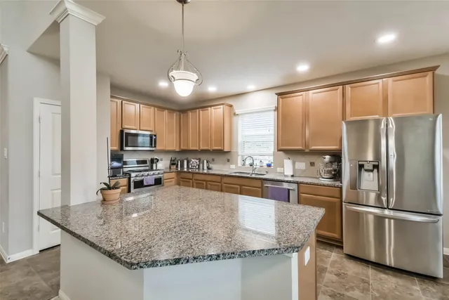 a kitchen with stainless steel appliances granite countertop a sink dishwasher stove top oven and refrigerator