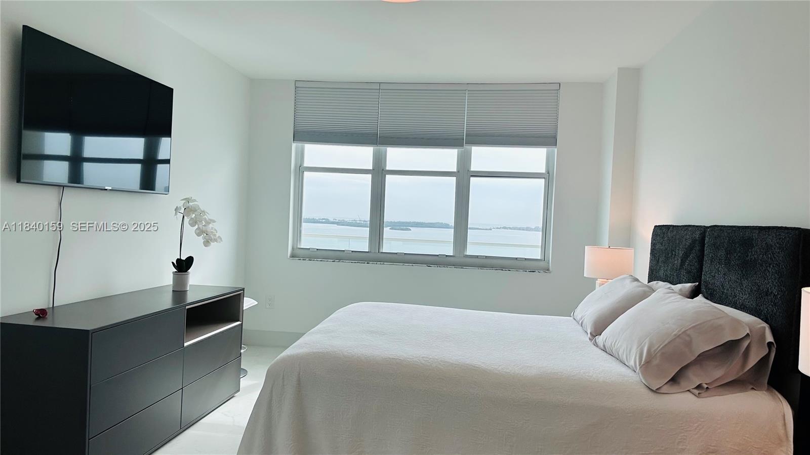 800 Claughton Island Drive, Unit 1903 Miami, FL 33131 - Photo 30 of 34 a bedroom with a bed and a flat tv screen on the dresser