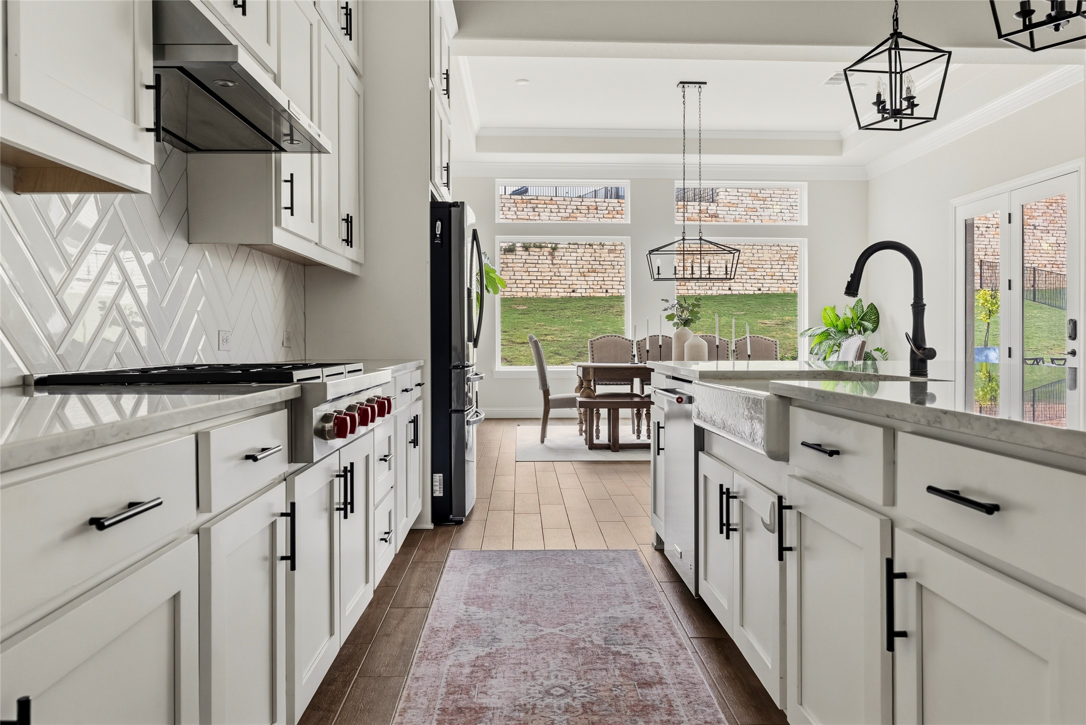 4513 Vieste View Leander, TX 78641 - Photo 19 of 40 Kitchen featuring white cabinetry, a large farmhouse sink, stainless steel appliances, and wood-finish flooring