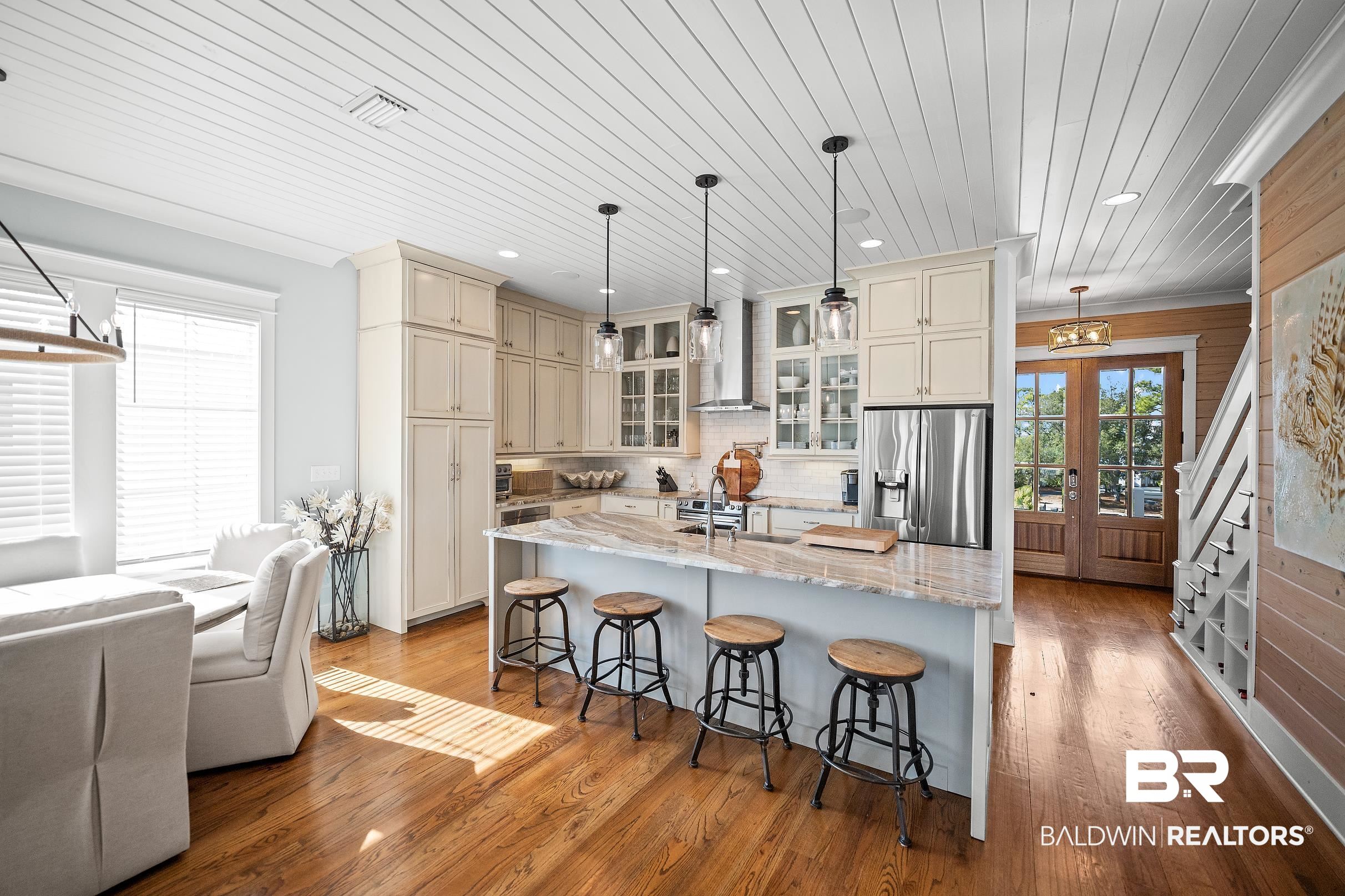 33186 Marlin Key Drive Orange Beach, AL 36561 - Photo 34 of 87 Kitchen with cream cabinets, light stone counters, pendant lighting, an island with sink, and stainless steel refrigerator with ice dispenser