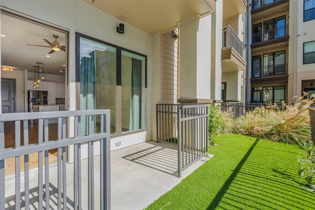 2700 Old Denton Road, Unit 1044 Carrollton, TX 75007 - Photo 18 of 33 Ground-level patio featuring artificial turf, metal railings, and natural landscaping