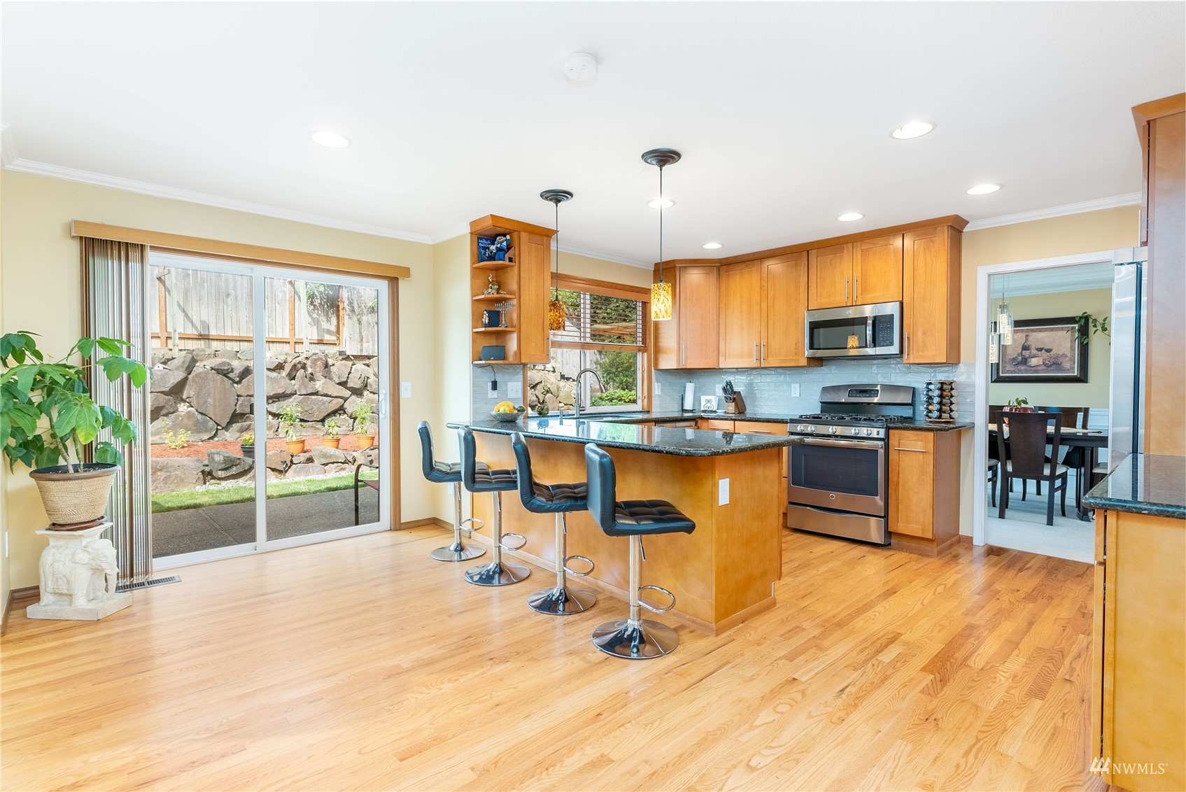 1807 Field Avenue Northeast Renton, WA 98059 - Photo 20 of 38 a kitchen with stainless steel appliances kitchen island granite countertop a refrigerator a stove top oven and a dining table with wooden floor