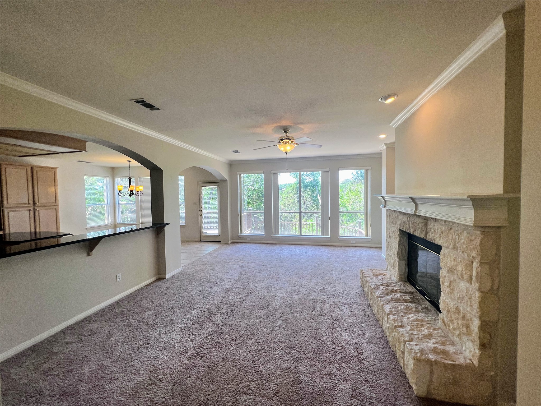9405 Ashton Ridge Austin, TX 78750 - Photo 4 of 22 A welcoming living room featuring a stone fireplace and picturesque outdoor views through numerous windows.