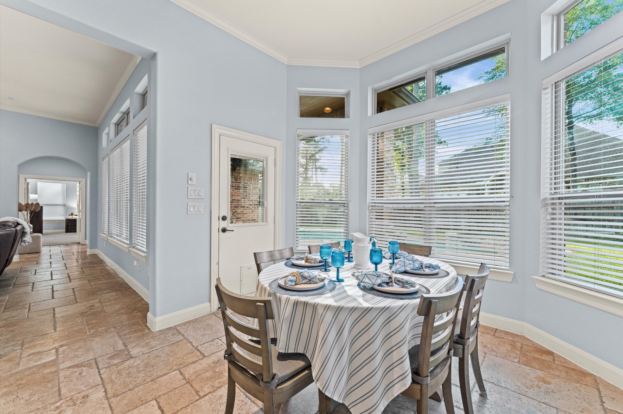 70 Valera Ridge Drive Spring, TX 77389 - Photo 20 of 37 This dining area features large windows providing ample natural light and views of the outdoors. It has a cozy setup with a round table, modern decor, and easy access to the adjacent living space. The light blue walls and tiled floor create a bright and welcoming atmosphere.