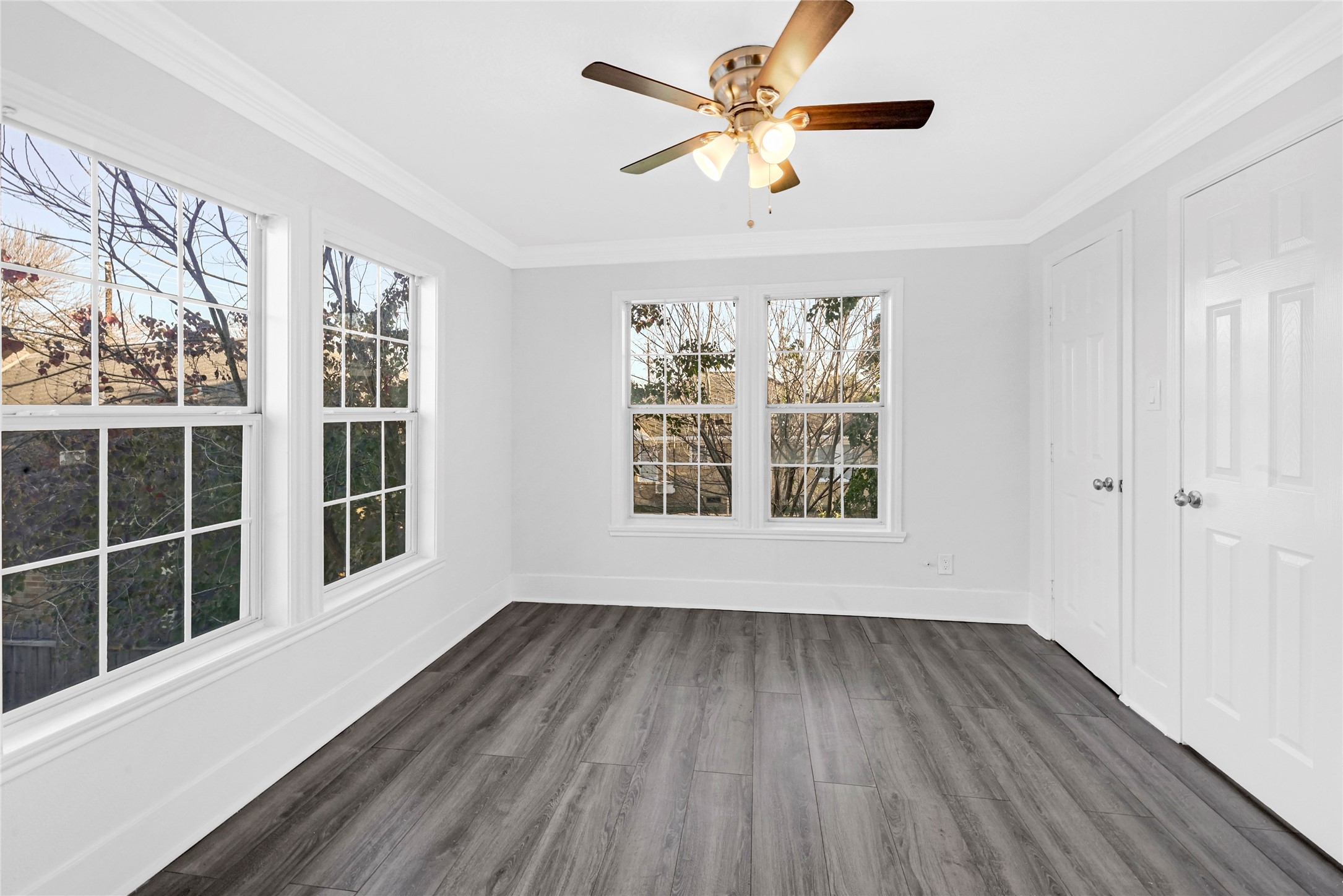 1633 Fourcade Street, Unit C Houston, TX 77023 - Photo 2 of 7 Bright room with large windows, modern gray flooring, and a ceiling fan. Perfect for a cozy bedroom or home office.