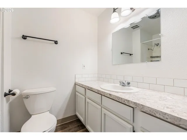 a bathroom with a granite countertop toilet sink and mirror