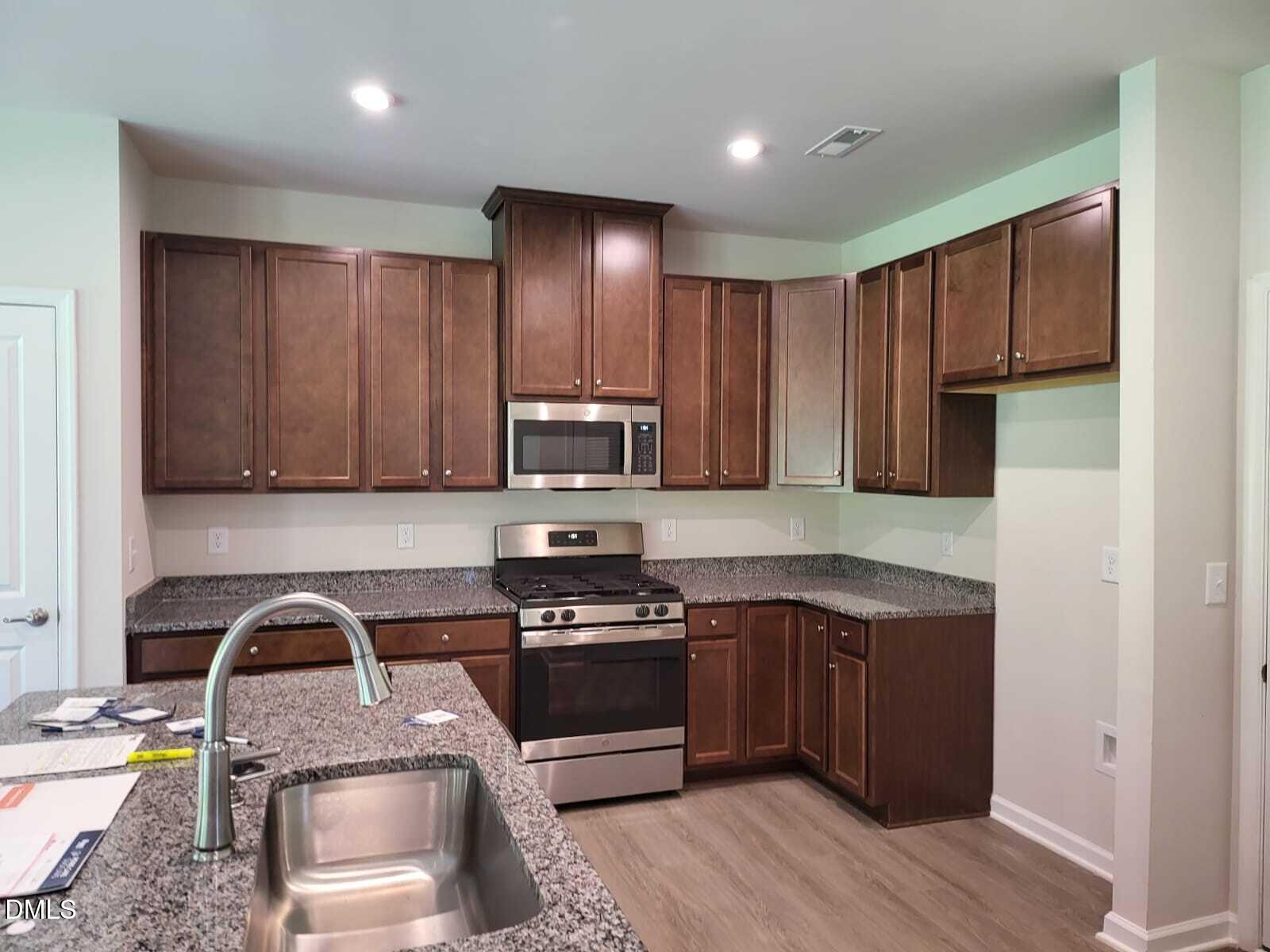 1740 Ripley Woods Street Wake Forest, NC 27587 - Photo 4 of 20 a kitchen with stainless steel appliances granite countertop a stove a sink dishwasher and a refrigerator with wooden floor
