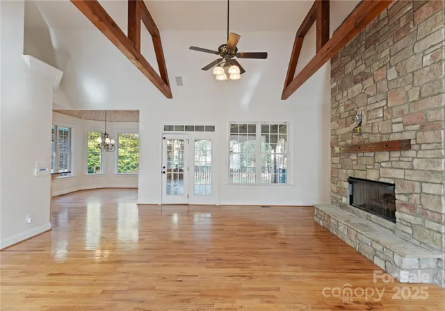 a view of an empty room with window and wooden floor