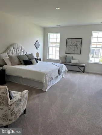 a spacious bedroom with a bed a couch and windows