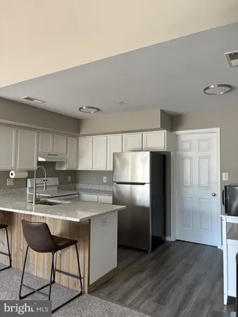 a kitchen with stainless steel appliances granite countertop a refrigerator a sink a stove a dining table and chairs