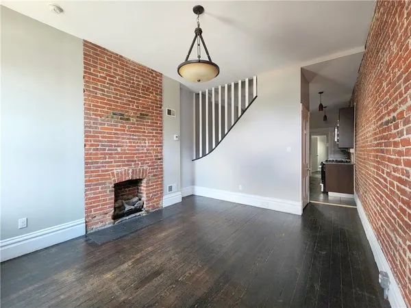 an empty room with wooden floor fireplace and windows