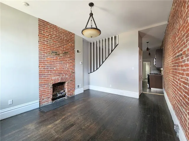 an empty room with wooden floor fireplace and windows