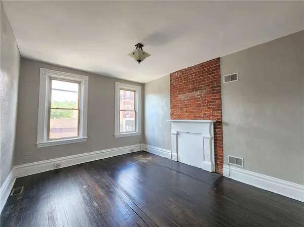 a big room with wooden floor a chandelier fan and windows