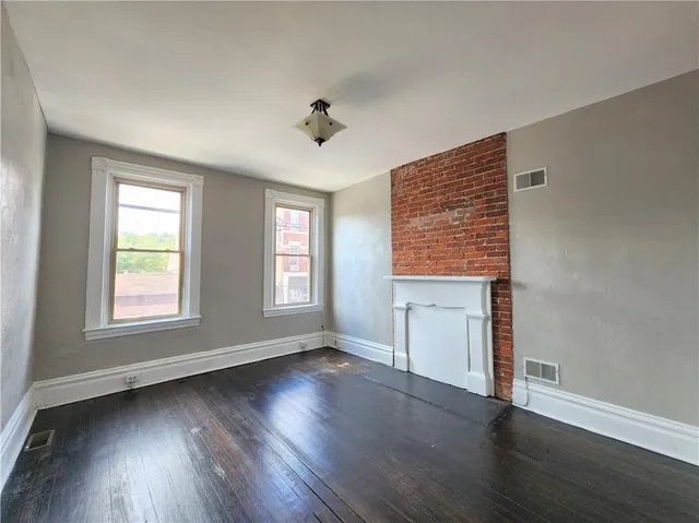 a big room with wooden floor a chandelier fan and windows