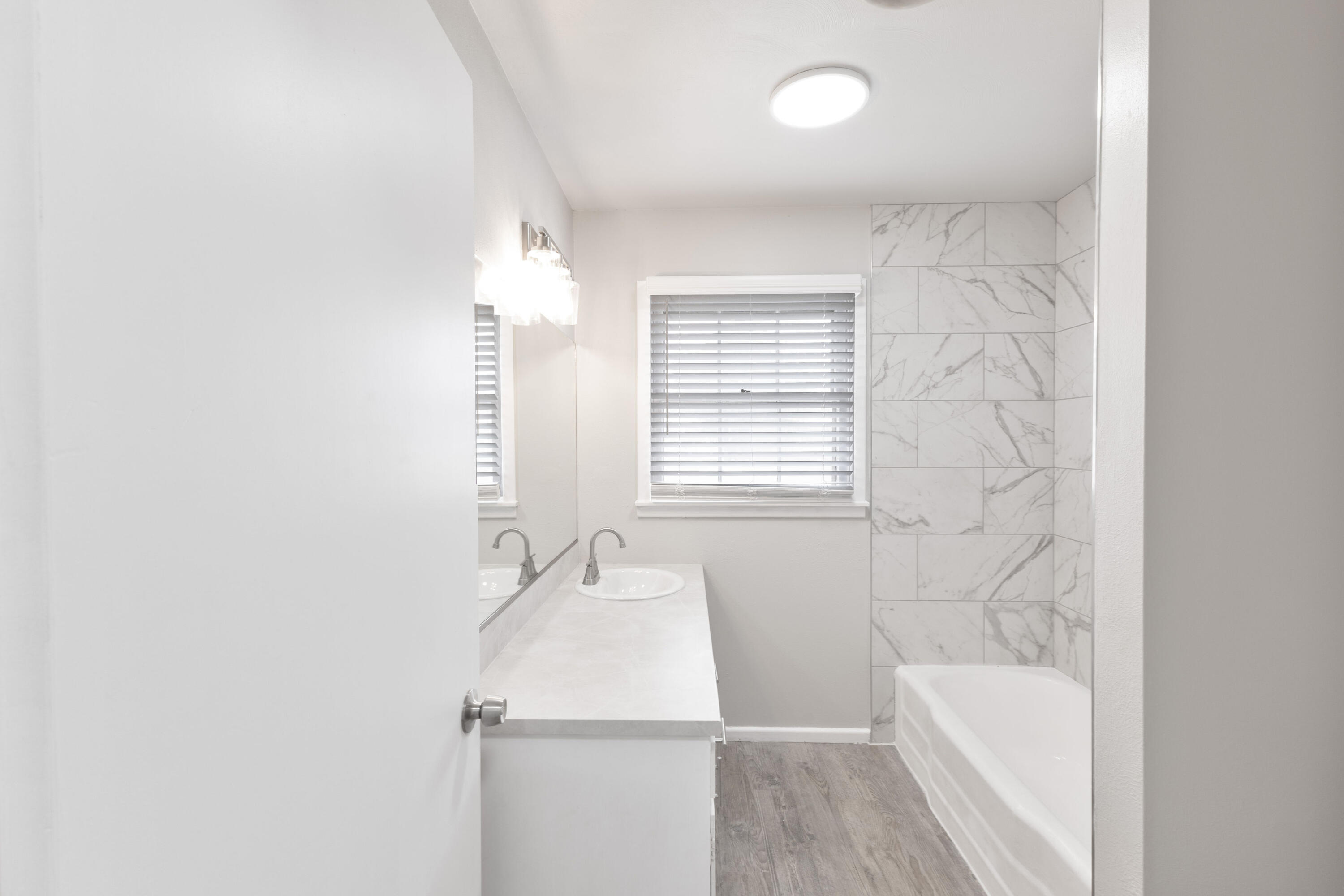 3417 52nd Street Lubbock, TX 79413 - Photo 14 of 19 a bathroom with a tub a sink and a window