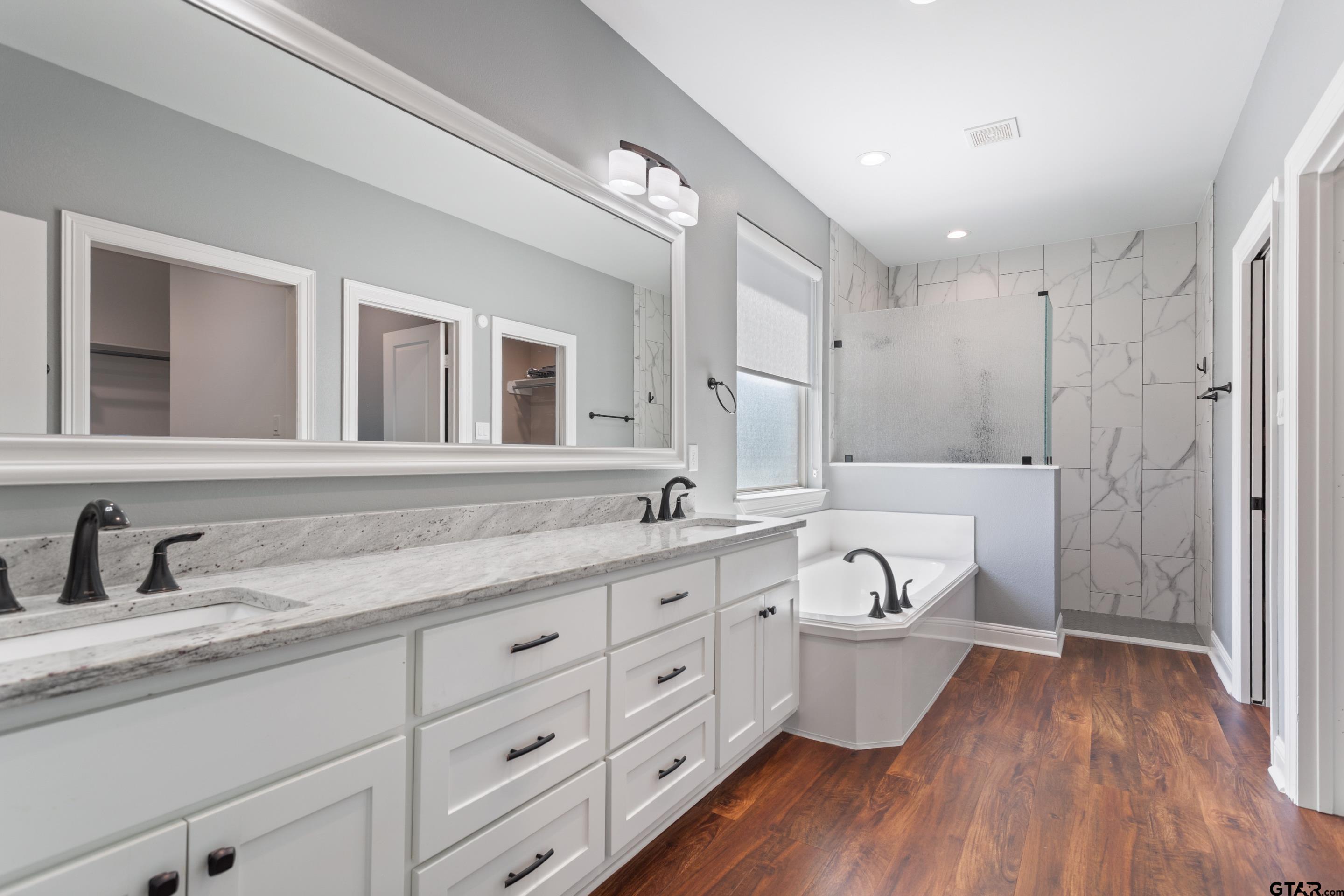 105 Nathan Road Chandler, TX 75758 - Photo 17 of 36 a spacious bathroom with double vanity a mirror a lamp and a bathtub