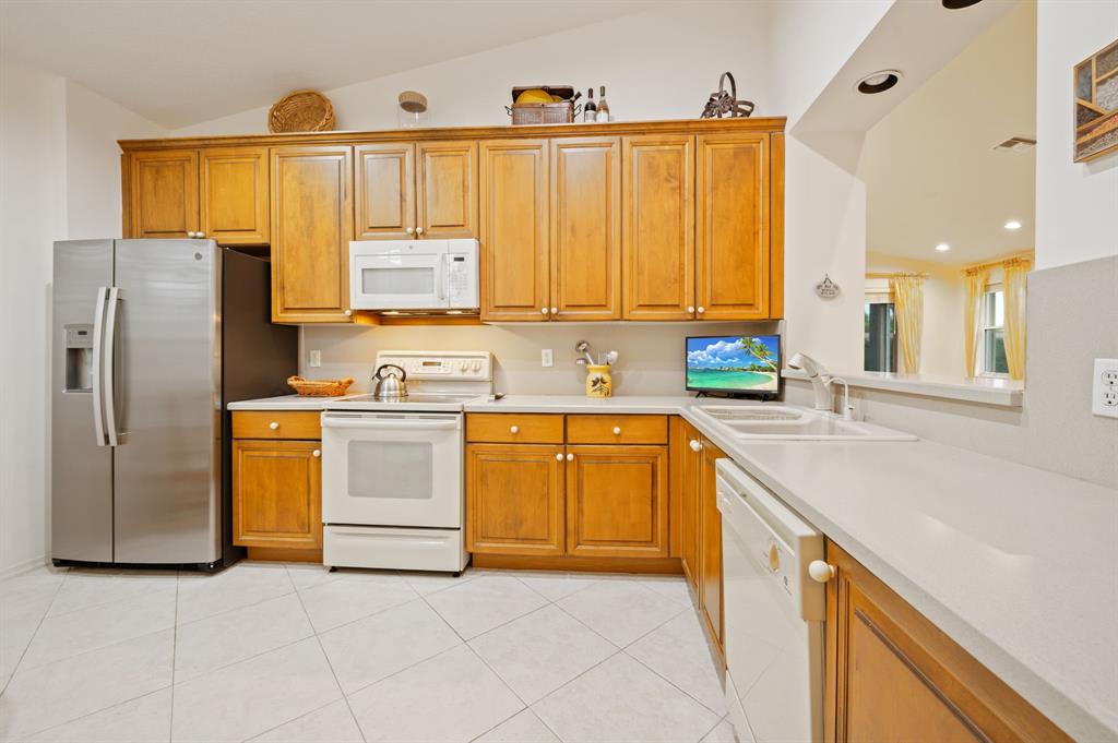 6710 Vía Roma Delray Beach, FL 33446 - Photo 11 of 35 a kitchen with stainless steel appliances granite countertop a sink and a refrigerator