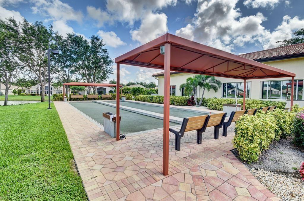 6710 Vía Roma Delray Beach, FL 33446 - Photo 31 of 35 a view of a patio with table and chairs under an umbrella
