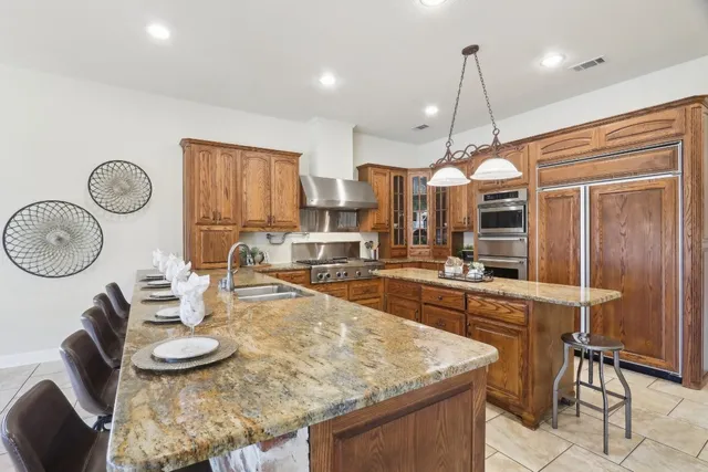 a kitchen with a stove a sink dishwasher a kitchen island with wooden cabinets and floor