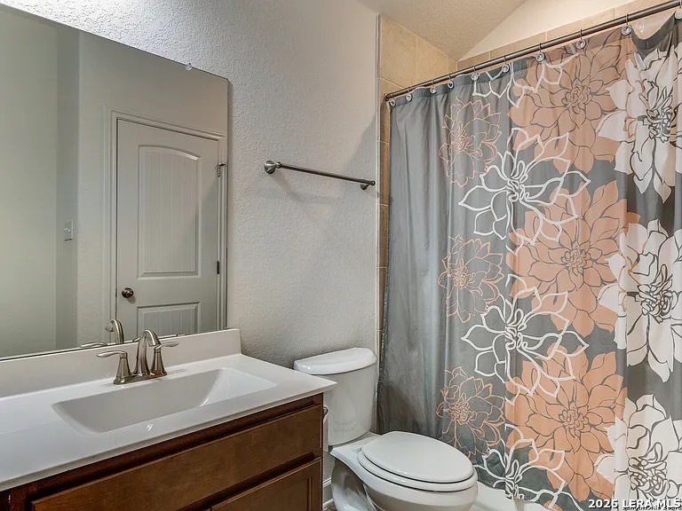 390 Rhapsody View Spring Branch, TX 78070 - Photo 27 of 28 a bathroom with a sink a toilet and shower curtain
