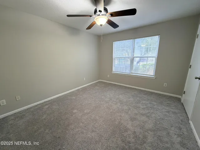 an empty room with windows and fan