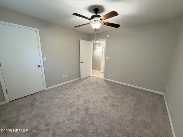 an empty room with a ceiling fan and a window