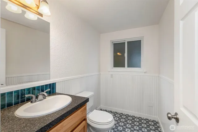 a bathroom with a granite countertop sink a mirror and a toilet