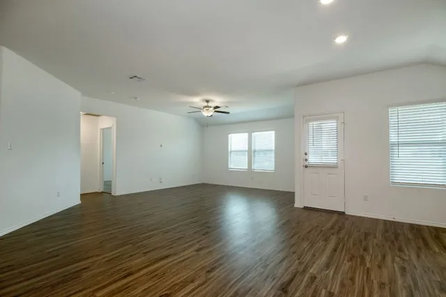 an empty room with wooden floor chandelier and windows
