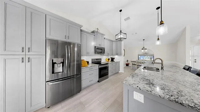 a kitchen with kitchen island a counter top space a sink stainless steel appliances and cabinets