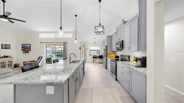 a large kitchen with stainless steel appliances kitchen island granite countertop a lot of counter space and wooden floors