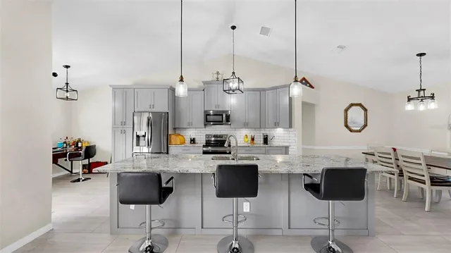 a kitchen with stainless steel appliances kitchen island granite countertop a stove a sink and a chairs