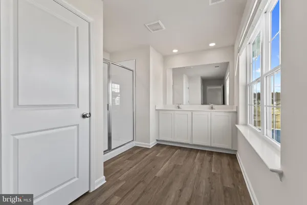 a view of a hallway with wooden floor and a bathroom