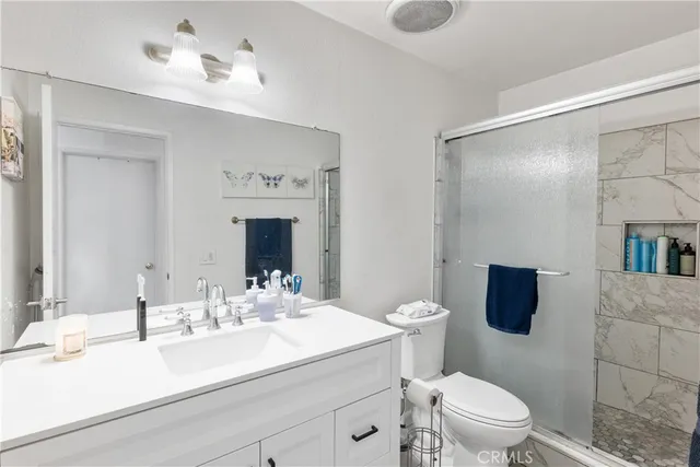 a bathroom with a sink vanity granite toilet and a mirror