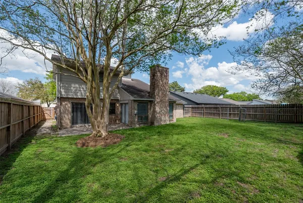 a view of a house with a yard and large trees