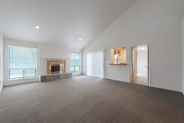 an empty room with windows and fireplace