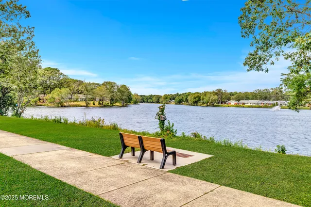 a view of a lake with lawn chairs and a table