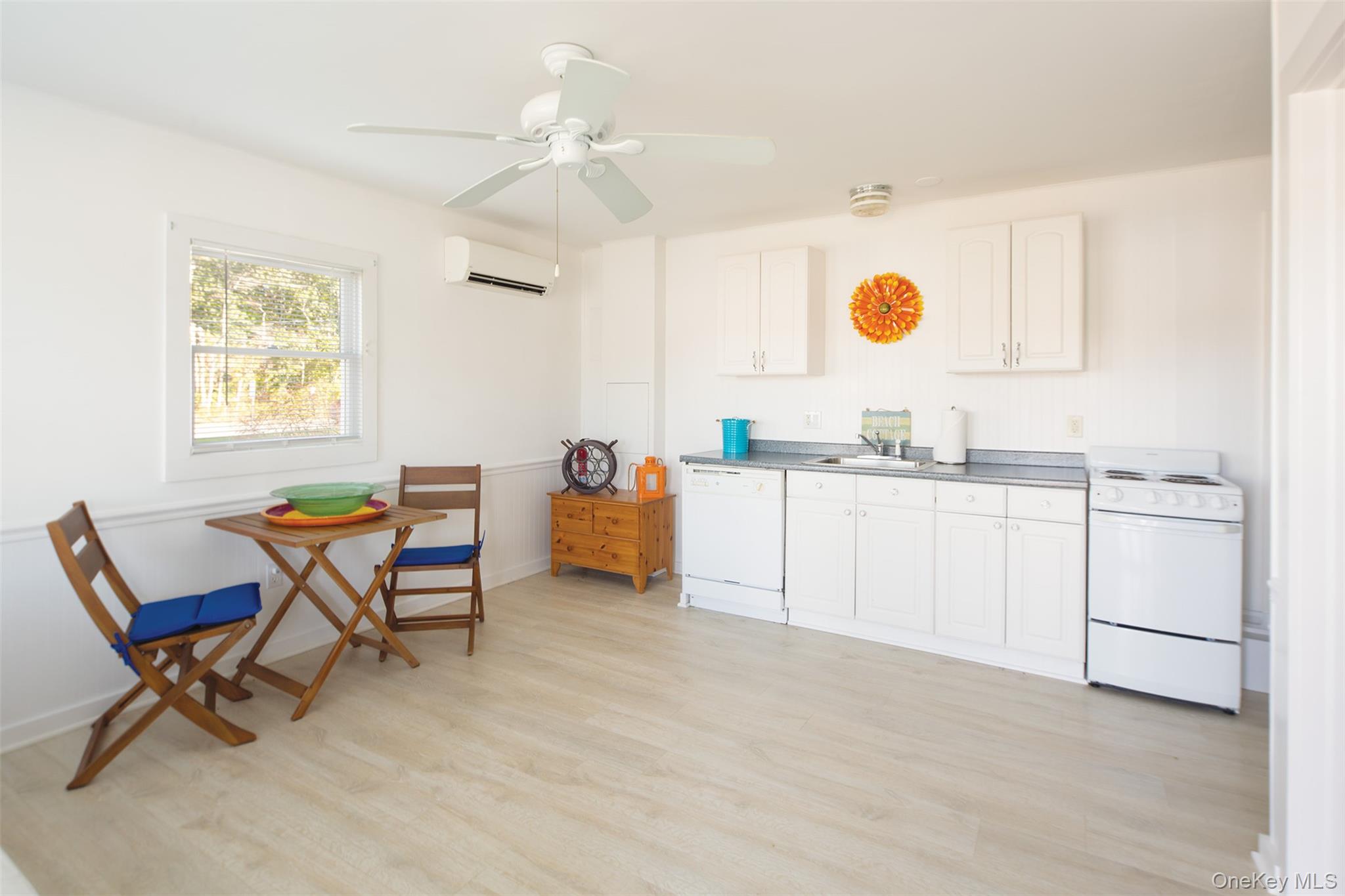 1 Canal Road Hampton Bays, NY 11946 - Photo 38 of 50 Kitchen with white appliances, light wood finished floors, white cabinetry, ceiling fan, and a wall mounted air conditioner