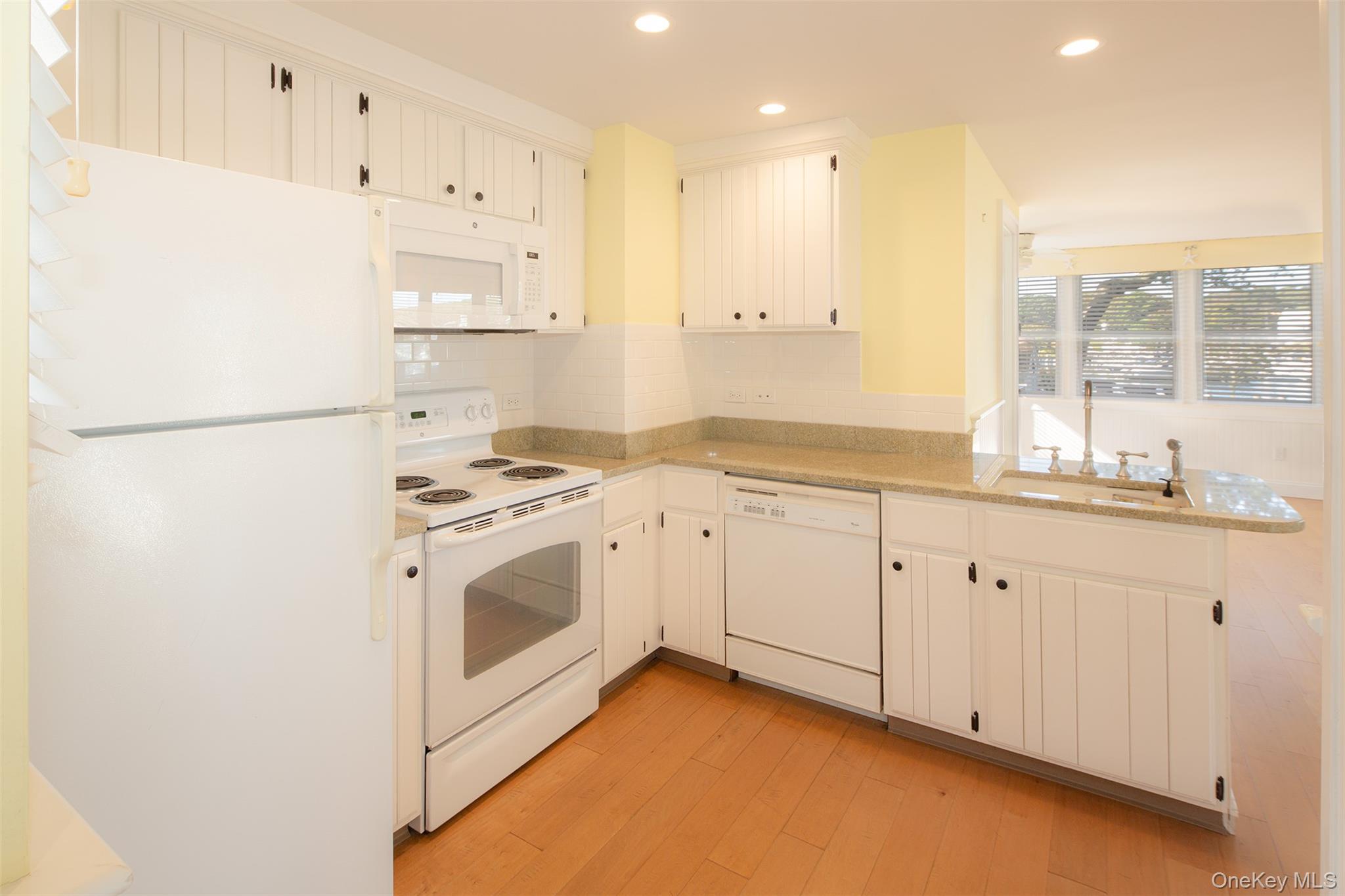 1 Canal Road Hampton Bays, NY 11946 - Photo 9 of 50 Kitchen featuring white appliances, a peninsula, light wood-style flooring, recessed lighting, and decorative backsplash